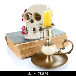 Schädel mit getrockneten Rosen auf altes Buch und Kerze isoliert auf weißem Stockfoto