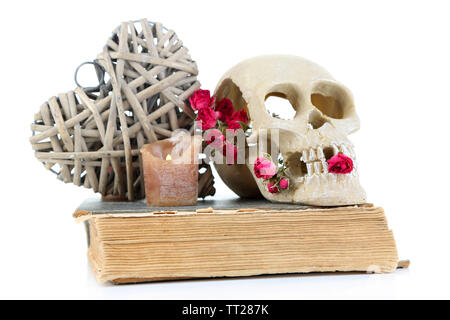 Schädel, wicker Herz und getrocknete Rosen auf altes Buch isoliert auf Weiss. Konzeptionelle Foto der Liebe Magie Stockfoto
