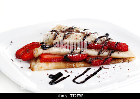 Leckere Pfannkuchen mit Erdbeeren und Schokolade auf der Platte isoliert weißer Stockfoto