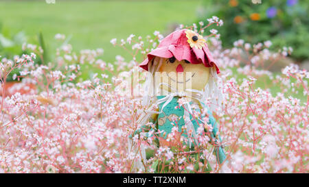 Eine Neuheit Vogelscheuche garten Ornament auf einem Schaft in einem Blumenbeet innerhalb einer inländischen Garten positioniert Stockfoto