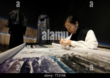 Junge Frau nähen traditionelle Seidenstickerei in einer Lagerhalle des ehemaligen Weingut wurde umgewandelt in eine multifunktionale Kultur Komplex namens Huashan 1914 Creative Park in Zhongzheng District, Taipei, Taiwan Stockfoto