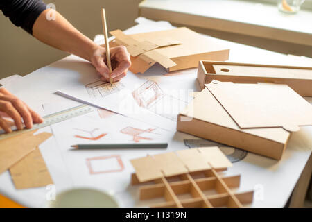 Designer zeichnet ein Mockup für Handwerk Karton. Entwicklung des Verpackungsdesigns Skizze. Stockfoto