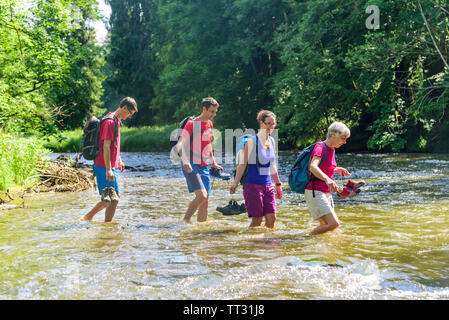 Eine Gruppe von Menschen Waten in einem Flussbett an einem heißen Sommertag im Allgäu Stockfoto