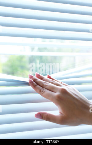 Weibliche Hand trennen Lamellen von Jalousien mit einem Finger durch zu sehen Stockfoto