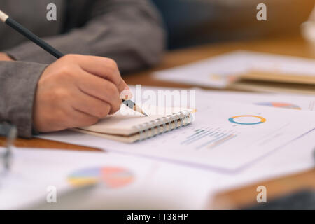 Eine Geschäftsfrau schreiben auf Notebook und Arbeiten an geschäftlichen Daten und Dokument auf dem Tisch im Büro Stockfoto