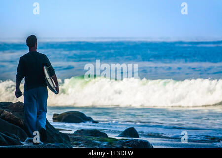 SIlhouetted Surfer Spaziergänge in Richtung Ozean mit einem Surfbrett Stockfoto