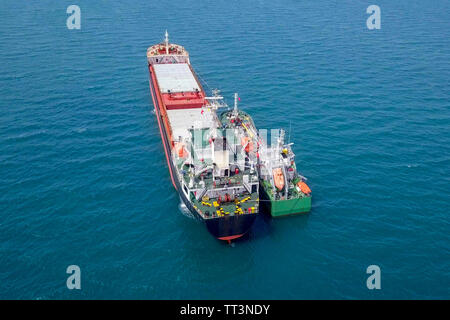 Tanken auf See - Kleine Öl Produkte Betankung einen großen Bulk Carrier, Luftbild. Stockfoto