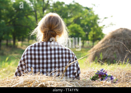 Schöne Mädchen sitzen auf haystack im Feld Stockfoto