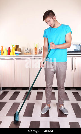 Junger Mann Reinigung Boden im Zimmer Stockfoto