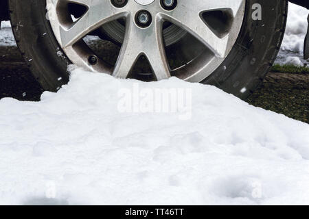 Schnee Haufen und einem geparkten Auto Rad auf verschneiten Morgen Stockfoto