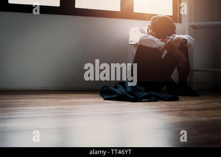 Allein betätigt man in der Ecke dunklen Zimmer sitzen wegen eines Problems und Traurigkeit im Leben Stockfoto