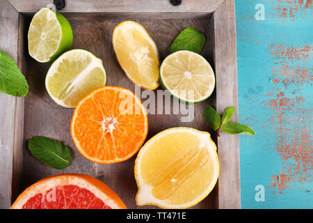 Anders geschnitten saftige Zitrusfrüchte auf Fach, auf blauen Holztisch Stockfoto