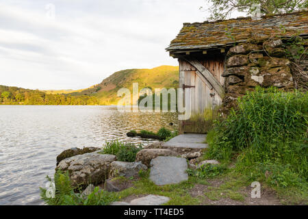 Grasmere, Lake District, Cumbria, Großbritannien: Im Hintergrund fiel ein steinernes Bootshaus mit Schieferdach und Holztür an der Seite von Grasmere mit Loughrigg. Stockfoto