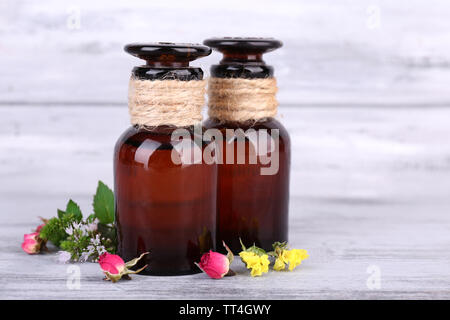 Ätherisches Öl mit verschiedenen Heilpflanzen, auf hölzernen Hintergrund Stockfoto