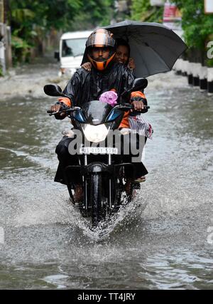 Guwahati, Assam, Indien. Juni 14, 2019. Pendler durch eine überflutete Straße Wade nach schweren Regenfaellen in Guwahati, Assam, Indien am Freitag, 14. Juni 2019. Quelle: David Talukdar Alamy leben Nachrichten Stockfoto