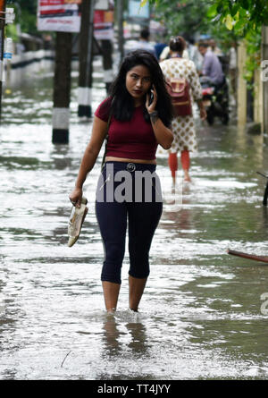 Guwahati, Assam, Indien. Juni 14, 2019. Pendler durch eine überflutete Straße Wade nach schweren Regenfaellen in Guwahati, Assam, Indien am Freitag, 14. Juni 2019. Quelle: David Talukdar Alamy leben Nachrichten Stockfoto