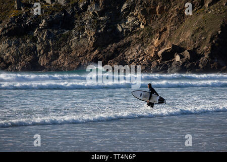 Surfer Witz ein Surfbrett im Meer am Strand Plage de la Baie des Trépassés an der Pointe du Raz, dem westlichsten Punkt von Frankreich Stockfoto