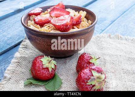 Frisches hausgemachtes Müsli, Müsli mit Erdbeeren in eine Platte auf einem blauen Hintergrund, selektiver Fokus Stockfoto
