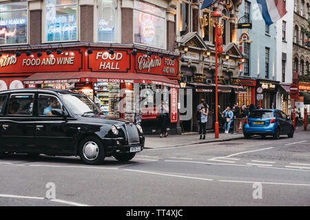 London, Großbritannien - 5. Juni 2019: Black Cab Antriebe in der Shaftesbury Avenue, vorbei an den Geschäften von Chinatown, London. Chinatown ist die Heimat einer Ostasiatischen Gemeinschaft ein Stockfoto