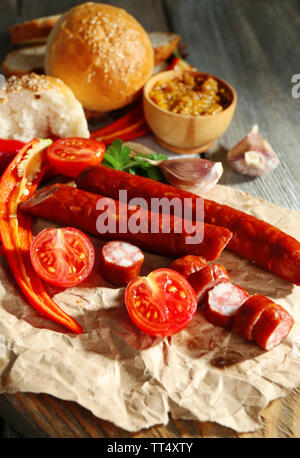 Dünne geräucherte Wurst und Gemüse auf ein Schneidbrett, auf hölzernen Hintergrund Stockfoto