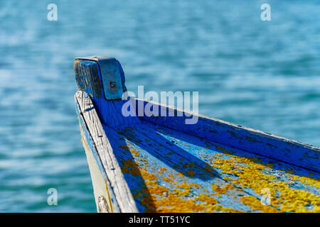 Nahaufnahme eines alten verwitterten Boot vorne mit abgebrochenen blaue Farbe und lebhaften Orange flechten friedlich Festlegung im Wasser (Oberseite, horizontal l Stockfoto