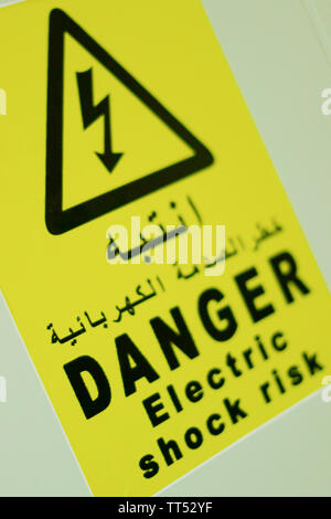 Stromschlag Gefahr, Gefahr Schild Aufkleber in schwarz Schreiben auf Arabisch schreiben auch mit gelbem Hintergrund Stockfoto