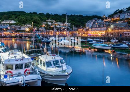 Nach dem anderen kühlen bewölkten Tag die Lichter flackern auf wie das Tageslicht in der Dämmerung in der historischen Fischerhafen von Looe, Cornwall. Stockfoto