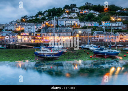 Nach dem anderen kühlen bewölkten Tag die Lichter flackern auf wie das Tageslicht in der Dämmerung in der historischen Fischerhafen von Looe, Cornwall. Stockfoto