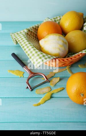 Zitronen und Orangen auf Serviette in Korb und Schälmesser auf Blau Holz- Hintergrund Stockfoto