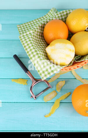 Zitronen und Orangen auf Serviette in Korb und Schälmesser auf Blau Holz- Hintergrund Stockfoto