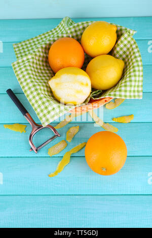 Zitronen und Orangen auf Serviette in Korb und Schälmesser auf Blau Holz- Hintergrund Stockfoto