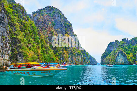 PHIPHI LEH, THAILAND - 27. APRIL 2019: Die Linie der touristischen Boote an den Klippen von Phi Phi Leh Insel; der Touristen genießen das klare Wasser der Bucht, auf Pileh Stockfoto