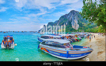 PHIPHI DON, THAILAND - 27. APRIL 2019: Die Küste mit Sandstrand, voll von Touristen und touristische Schnellboote, Anreise von Krabi und Phuket, Stockfoto