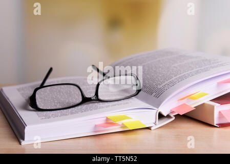 Bücher mit Lesezeichen und Gläser auf dem Tisch auf hellen Hintergrund Stockfoto