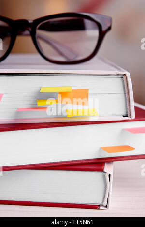 Bücher mit Lesezeichen und Gläser auf dem Tisch auf hellen Hintergrund Stockfoto