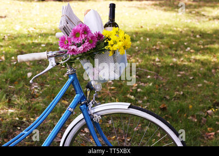 Fahrrad mit Blumen und einer Flasche Wein in Metall Korb auf Park Hintergrund Stockfoto