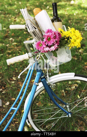 Fahrrad mit Blumen und einer Flasche Wein in Metall Korb auf Park Hintergrund Stockfoto