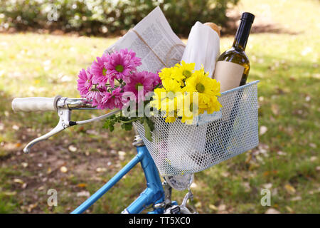 Fahrrad mit Blumen und einer Flasche Wein in Metall Korb auf Park Hintergrund Stockfoto
