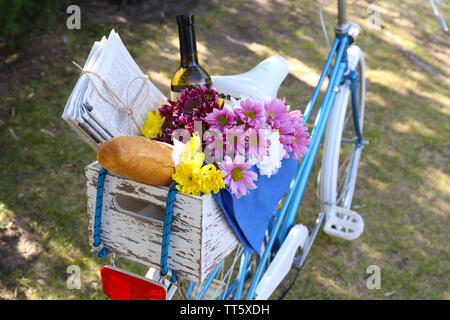 Fahrrad mit Blumen, Brot und einer Flasche Wein im Holzkasten auf Gras Hintergrund Stockfoto