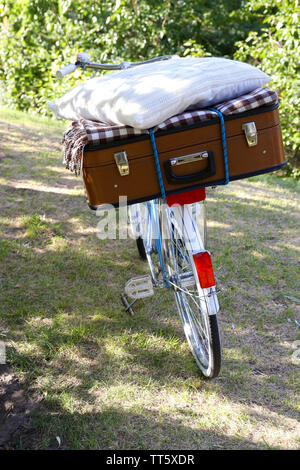 Fahrrad- und braunen Koffer mit Picknick im Schatten in Park Stockfoto