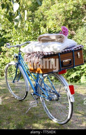 Fahrrad- und braunen Koffer mit Picknick im Schatten in Park Stockfoto