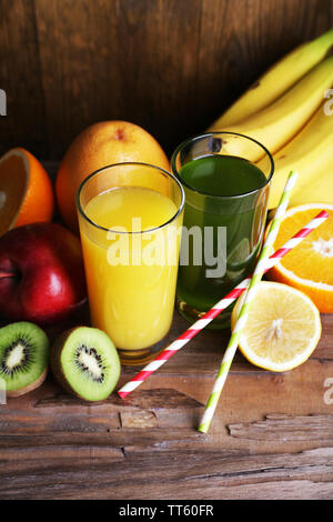 Banane und Kiwi Saft in Gläser und frische Früchte auf Holztisch auf Holz Wand Hintergrund Stockfoto