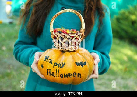 Junge Mädchen, dass Halloween Kürbis und Korb mit Süßigkeiten,, in der Nähe im Freien Stockfoto