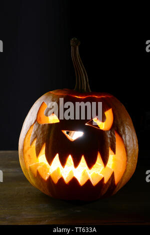 Halloween Kürbis auf dem Tisch auf schwarzem Hintergrund Stockfoto