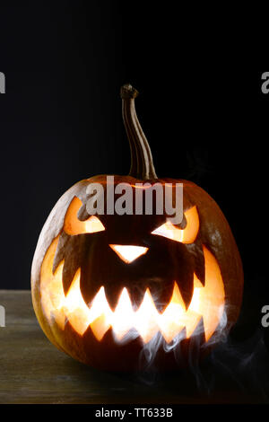 Halloween Kürbis auf dem Tisch auf schwarzem Hintergrund Stockfoto