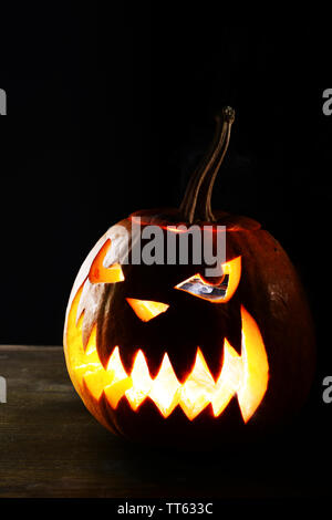 Halloween Kürbis auf dem Tisch auf schwarzem Hintergrund Stockfoto