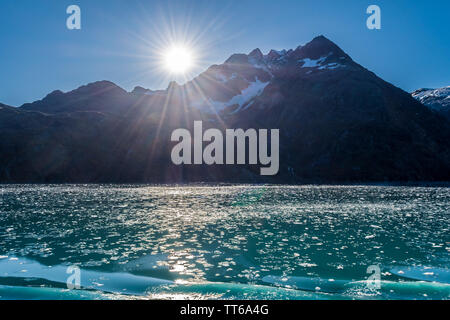 Die Brocken aus Eis von Gletschern Schwimmen im See. Die schneebedeckten Berge im Hintergrund an einem sonnigen Tag. Kreuzfahrtschiff Tour im Glacier Bay, Alaska Stockfoto