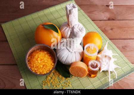 Spa noch Leben mit compress Kugeln und Kokosnussschalen auf Farbe Bambus matte und Holz- Hintergrund Stockfoto