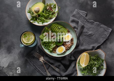 Vegan Buddha Schüssel mit Buchweizen, Avocado, gekochte Eier, Tomaten, Rucola Zuckerrüben Blätter, Zitrone. Gesunde, Detox, Diät Lebensmittel Konzept Stockfoto