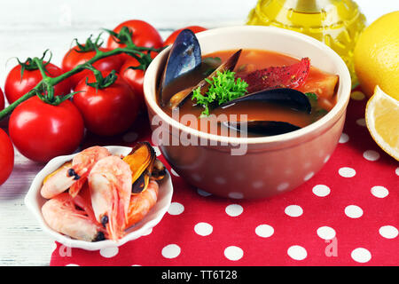 Lecker Suppe mit Garnelen, Muscheln, Tomaten und schwarzen Oliven in Schale auf Holz- Hintergrund Stockfoto